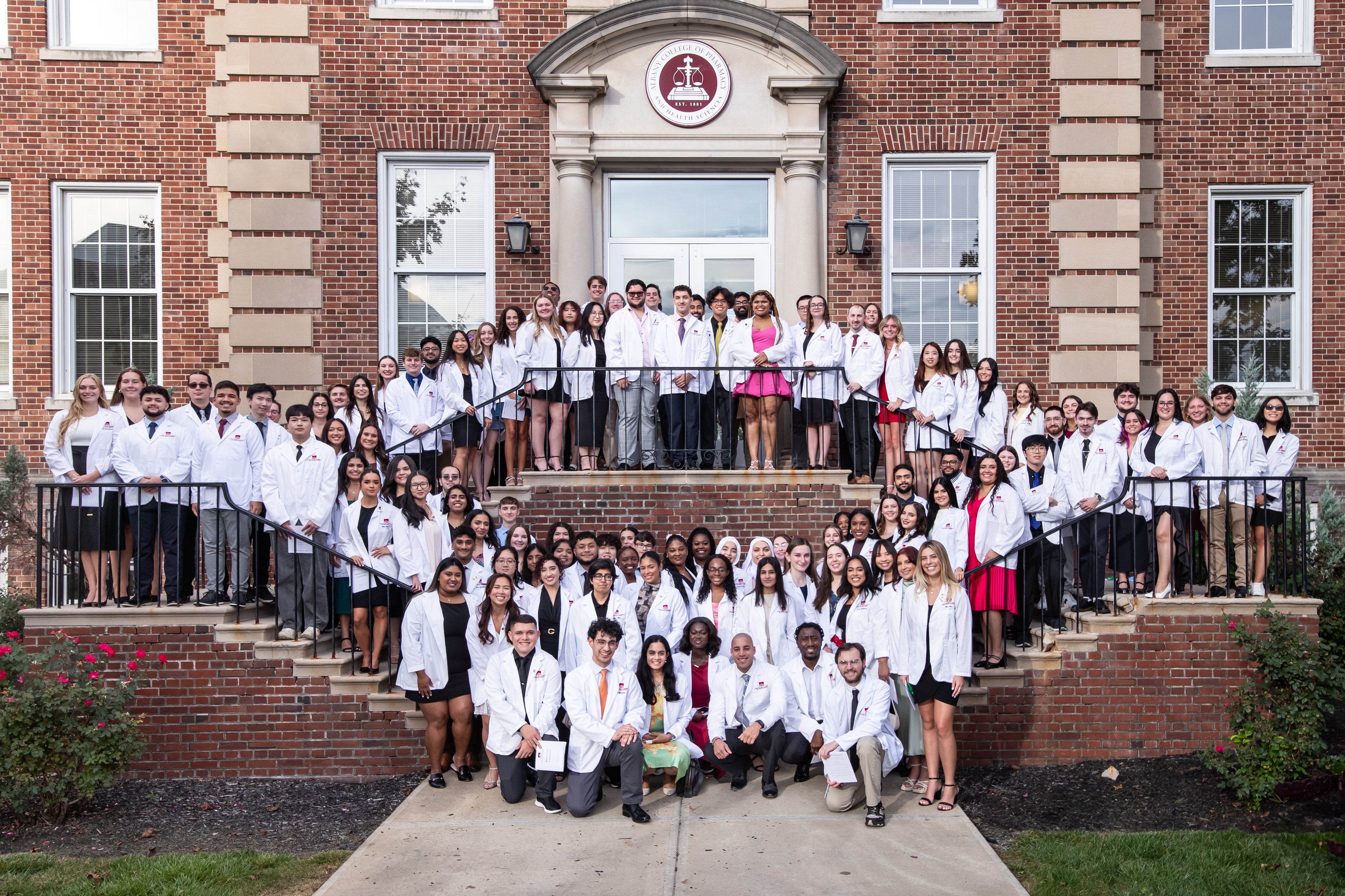 The Class of 2028 in their white coats on the library steps