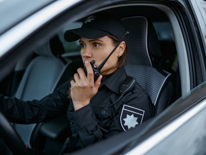 A cop speaks on walkie talkie while in vehicle