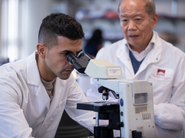 Student and professor examine microscope in lab